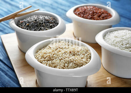 Different types of rice in bowls on wooden tray closeup Stock Photo