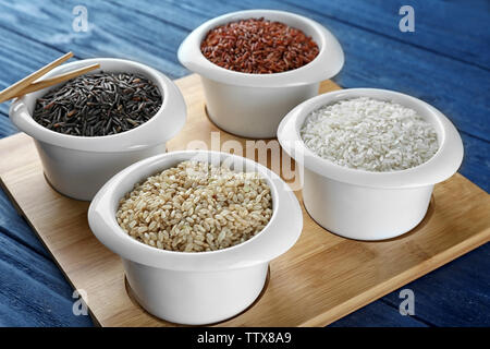 Different types of rice in bowls on wooden tray closeup Stock Photo