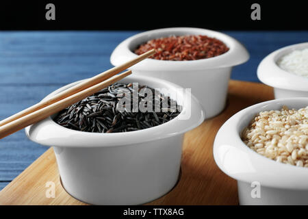 Different types of rice in bowls on wooden tray closeup Stock Photo