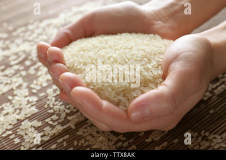 Female hands full of parboiled rice on bamboo mat background Stock ...