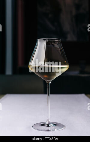 A beautiful glass on a long thin leg with white wine on a purple tablecloth Stock Photo