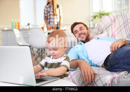 Cute baby boy using laptop under father control Stock Photo