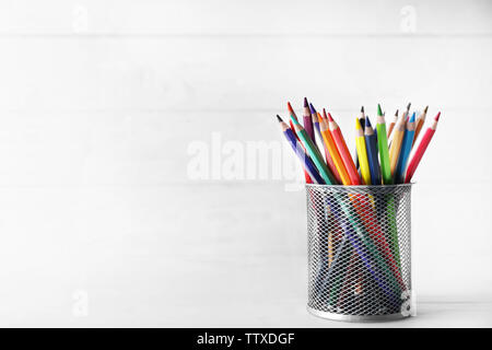 Crayons in metal holder on white wooden background Stock Photo
