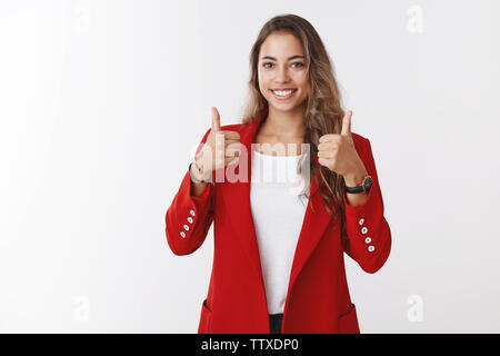 Nice job, well done, great. Proud good-looking satisfied female entrepreneur showing thumbs up smiling delighted pleased seeing good result Stock Photo