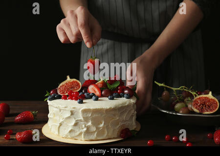 Baker hand decorating creamy cake on table Stock Photo