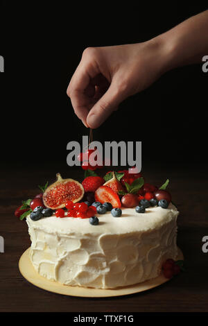 Baker hand decorating creamy cake on table Stock Photo