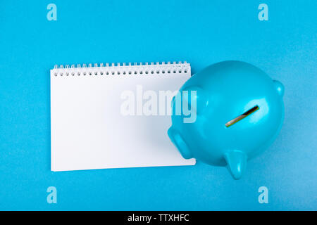 Top view of pink piggybank on blank white notebook Stock Photo