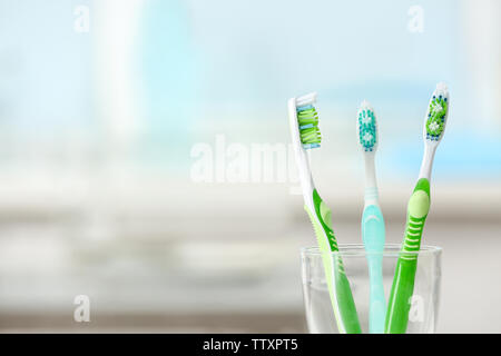 Toothbrushes in glass on blurred background Stock Photo