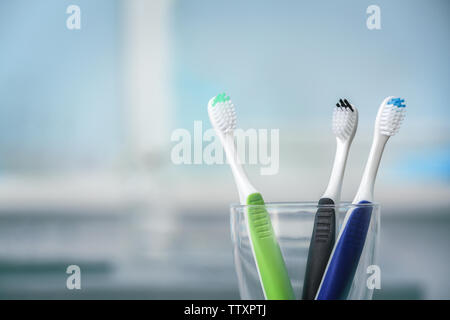 Toothbrushes in glass on blurred background Stock Photo