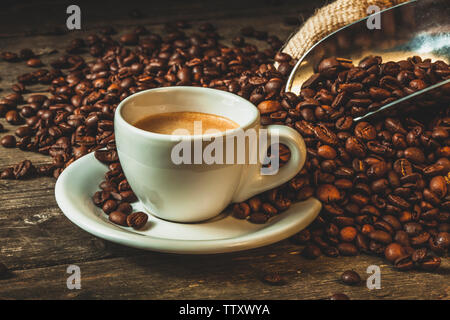 Coffee cup with roasted beans and jute sack on a natural wooden background. Stock Photo