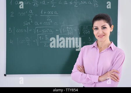 Young female teacher beside blackboard on white background Stock Photo