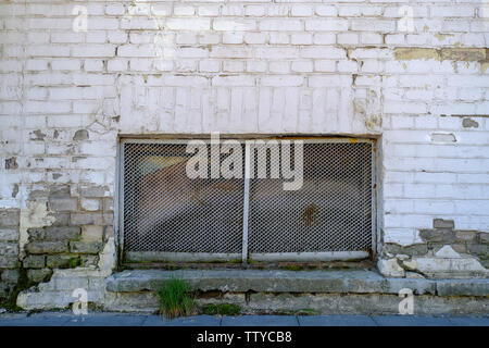 Small Windows of the basement. Brick wall, Windows covered with metal mesh Stock Photo