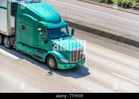 Bright green powerful professional American bonnet big rig industrial semi truck transporting frozen and chilled cargo in refrigerated semi trailer dr Stock Photo