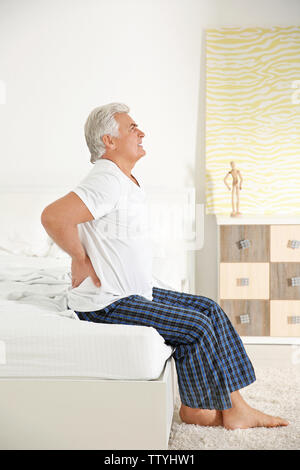 Senior gentleman suffering from pain in bedroom Stock Photo