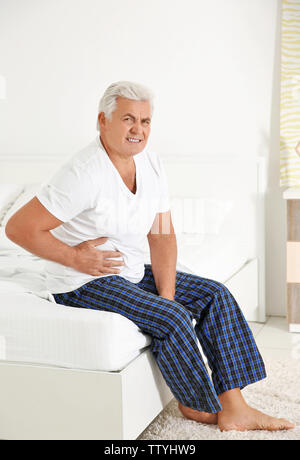 Senior gentleman suffering from pain in bedroom Stock Photo