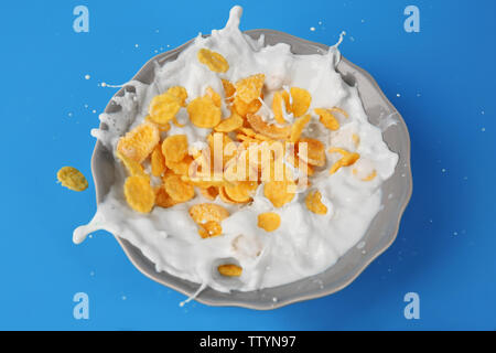 Corn flakes with milk in bowl on blue background Stock Photo