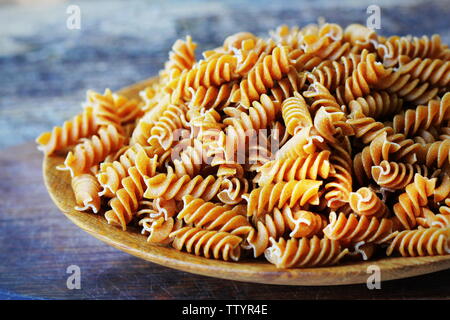 Wholemeal Fusilli in a plate. Integral Pasta over a wooden table Stock Photo
