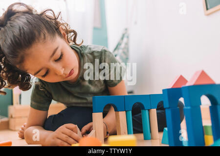 child little girl playing constructions on the floor with wooden building block toys at home or kindergarten, educational toys for creative children Stock Photo