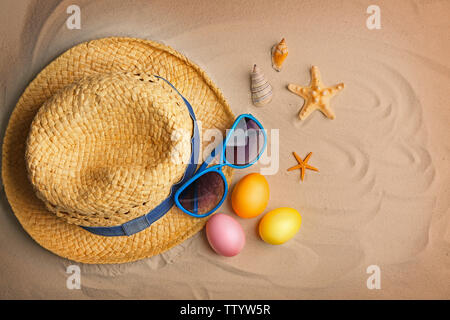 Easter eggs with sunglasses and hat on sand Stock Photo