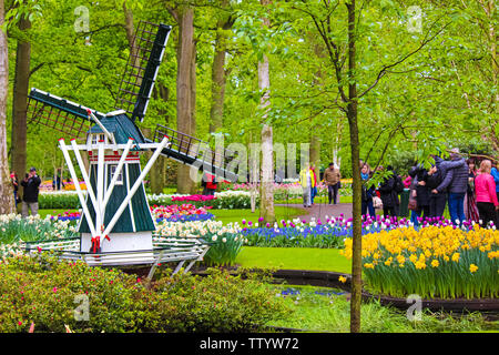 Keukenhof, Lisse, Netherlands - Apr 28th 2019: Famous Keukenhof gardens with windmill, colorful tulip flowers and visitors. Tulips in this famous park are major tourist attraction in Holland. Stock Photo