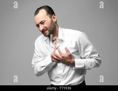 Handsome man having heart attack, on color background Stock Photo