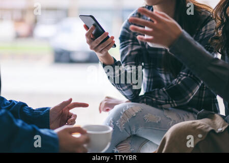 People using phone, talking and drinking coffee together Stock Photo