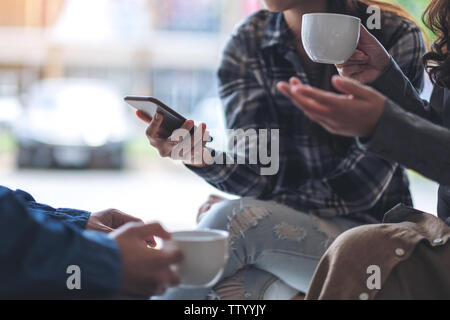 People using phone, talking and drinking coffee together Stock Photo