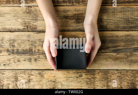 Female hands with black open box on wooden background Stock Photo