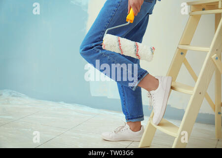 Young female decorator with paint roller in room, closeup Stock Photo