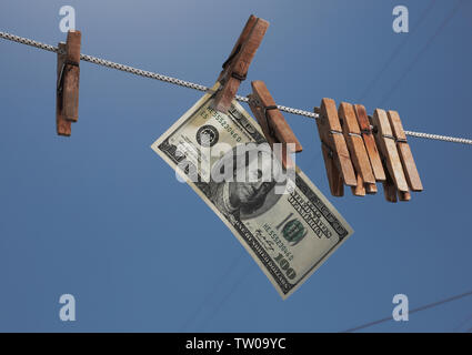Money Hanging On a Clothesline With Old Wooden Clothespins. The symbol of offshore investments, financial crimes and money laundering. Stock Photo