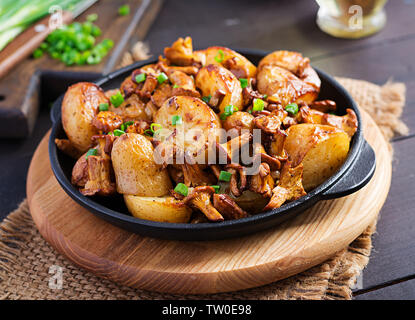 Baked potatoes with garlic, herbs and fried chanterelles in a cast iron skillet. Stock Photo