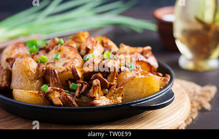 Baked potatoes with garlic, herbs and fried chanterelles in a cast iron skillet. Stock Photo