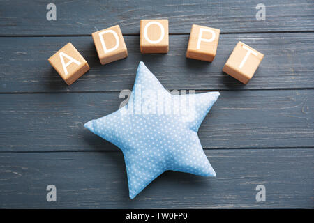 Cubes with word ADOPT and rag star on wooden background Stock Photo