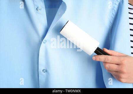 Woman cleaning shirt with adhesive roller Stock Photo