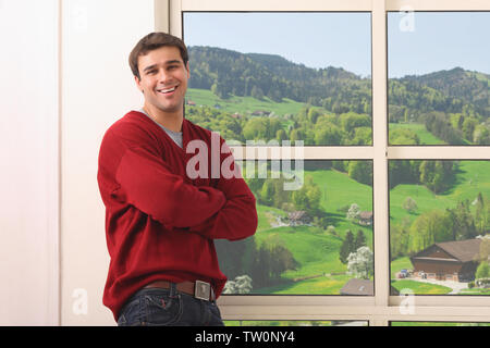 Portrait of a man standing by a window and smiling Stock Photo