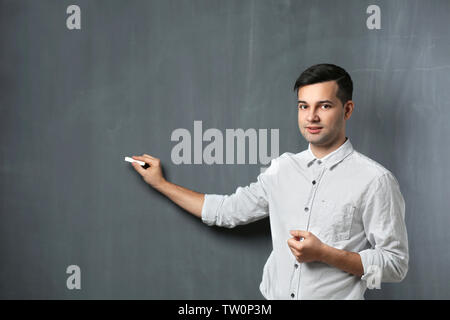 Handsome young teacher standing near blackboard Stock Photo
