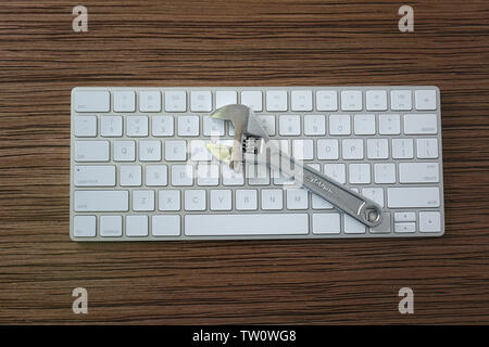 Modern wireless keyboard and adjustable wrench on wooden table Stock Photo
