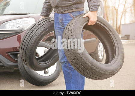 Man carrying two tires outdoors Stock Photo
