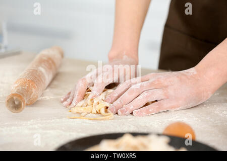 Woman preparing pasta on kitchen table, closeup Stock Photo