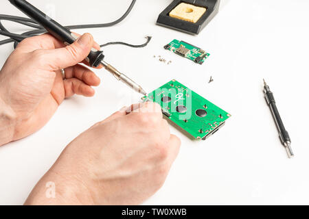 A person soldering a circuit board on a table Stock Photo