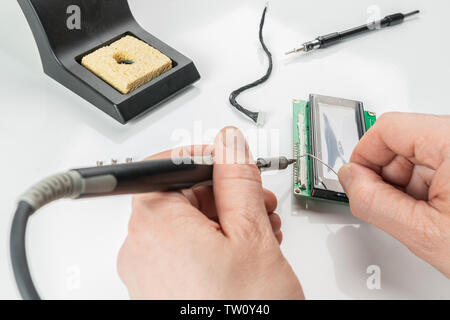 A person soldering an electronic component with a soldering iron Stock Photo