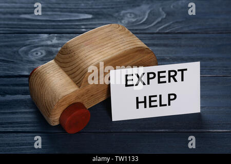 Phrase EXPERT HELP and toy car on wooden background Stock Photo