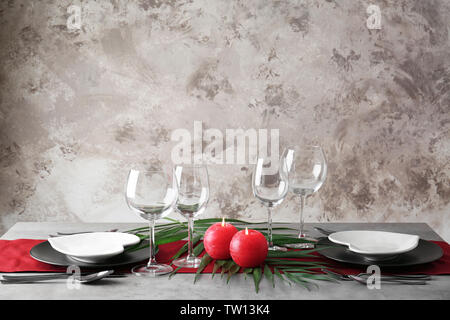 Table setting with plates in shape of heart and candles on color wall background Stock Photo