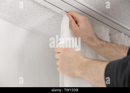 Male hands installing curtains over window Stock Photo