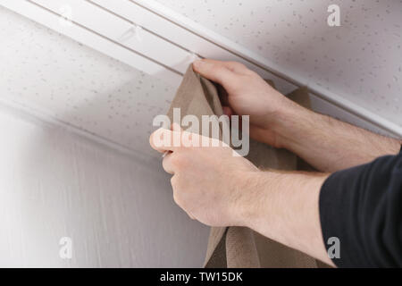 Male hands installing curtains over window Stock Photo