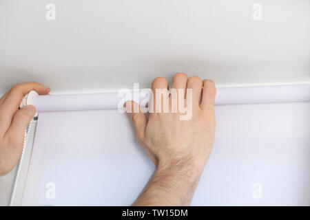 Male hands installing roller blinds on window Stock Photo