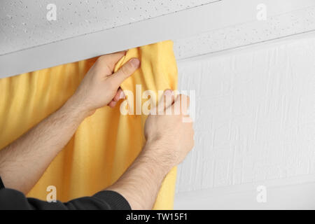 Male hands installing curtains over window Stock Photo