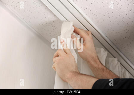 Male hands installing curtains over window Stock Photo