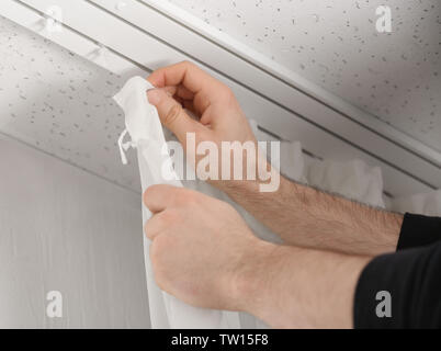 Male hands installing curtains over window Stock Photo