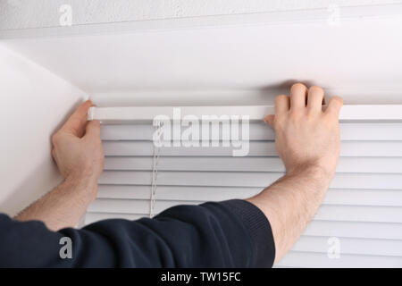 Male hands installing window blinds Stock Photo